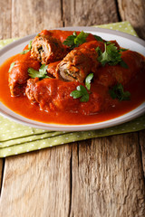 Italian beef steak braciole stuffed with parsley and cheese in tomato sauce close-up. vertical