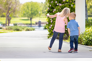 Young Sister and Brother Holding Hands And Walking At The Park
