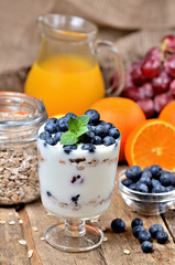 Bio yogurt with oatmeal, fresh blueberries, mint and orange juice, grapes in background vertical photo