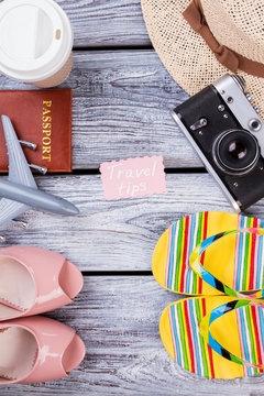 Travel tips flat lay. Top view, female shoes, flip flops, passport and straw hat.