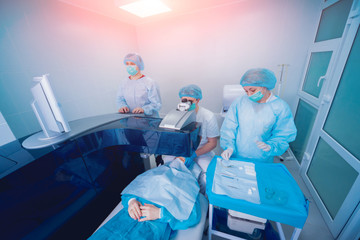 Laser vision correction. A patient and team of surgeons in the operating room during ophthalmic...
