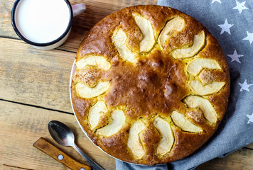 Apple cake on the plate and milk on a wooden table. Top view