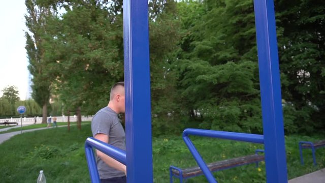 Professional male gymnast training on parallel bars outdoor.
