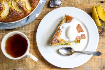 Apple cake on the plate with ice cream and tea on a wooden table. Top view