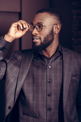 Positive confident businessman fixing his glasses