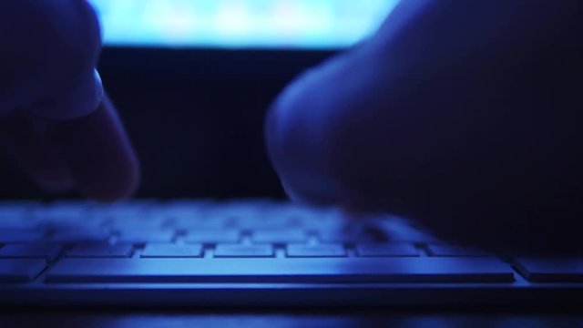 Hands typing text on the laptop keyboard. Night theme
