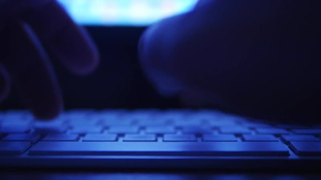 Hands typing text on the laptop keyboard. Night theme