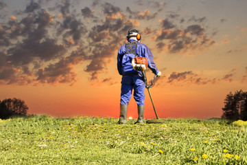 A man in a blue suit. In a protective helmet and headphones. Produces harvesting herbs. The face...