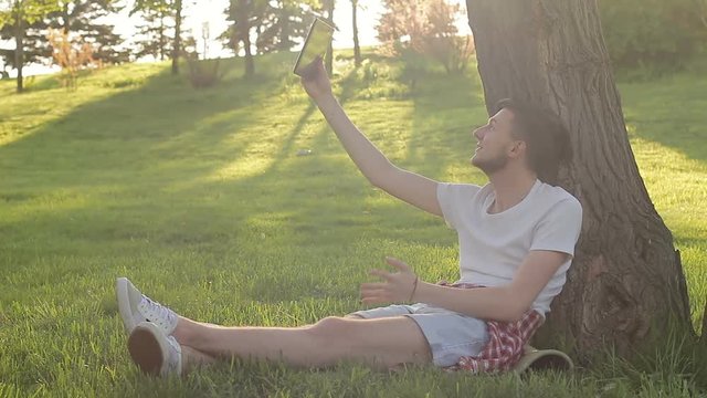 young guy emotionally communicating in skype on nature