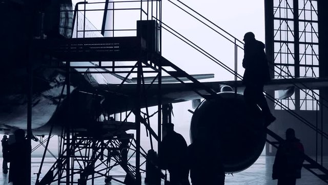 Engineers working with the aircraft in the hangar. Silhouette time lapse