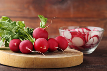 Red radishes on brown cutting board