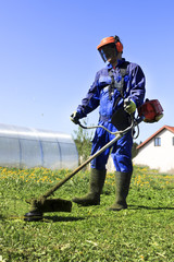 A man in a blue suit. In a protective helmet and headphones. Produces harvesting herbs. The face does not focus