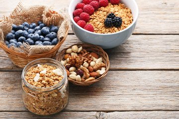 Tasty granola and berries and nuts on grey wooden table