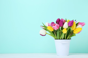 Bouquet of tulips in bucket on wooden table