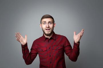 Portrait of young surprised man on grey background