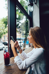 Profile of gorgeous woman, using a cell phone, texting a message, spending time with pleasure at...