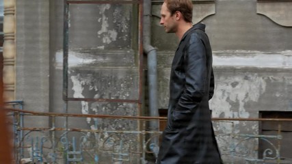 Soviet spy pursues a suspect with black long leather coat near old building poor district street - Powered by Adobe