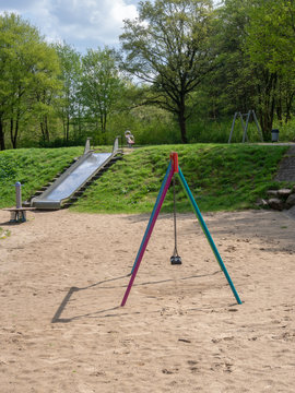 Blick auf Kinderspielpaltz mit Schaukeln, Rutsche, Wippe und Federwippe.