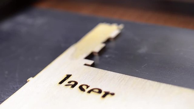 Laser engraving on wood. Industrial modern technological background. Printer laser burns the pattern on a wooden board.
