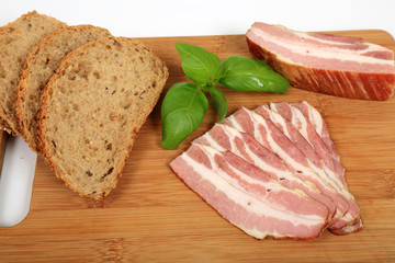 Wędzony boczek, pieczywo i bazylia na drewnianej desce. © Stanisław Błachowicz