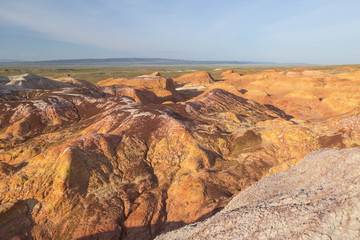 Travellers in the Multicolored red, orange and yellow striped hills under a bright blue sky in Eastern Kazakhstan