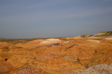 Small Multicolored red, orange and yellow striped hills under a bright blue sky in Eastern Kazakhstan