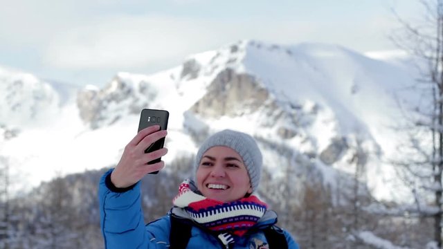 Young woman taking a self portrait with her smartphone in the mountains, Alps, Austria 