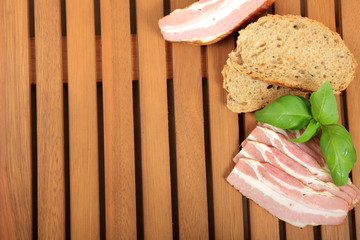 Wędzony boczek, pieczywo i bazylia na drewnianej tacy. © Stanisław Błachowicz