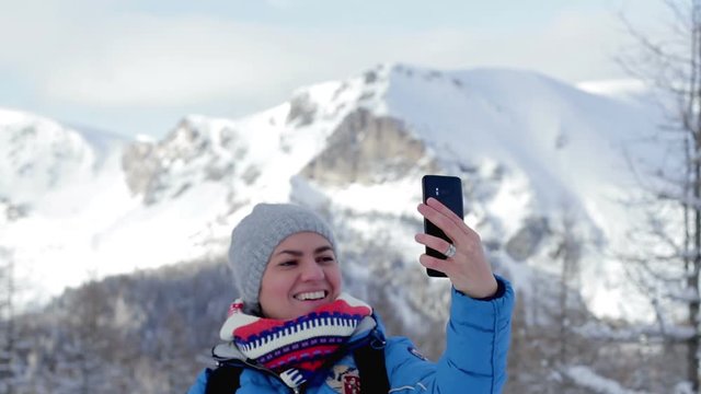 Young woman taking a self portrait with her smartphone in the mountains, Alps, Austria 