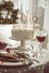 Table for two with white cake, chocolate biscuits and red wine