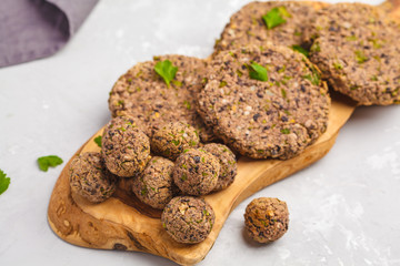 Vegan beans burgers (cutlets) and meatballs with parsley on a wooden board, top view copy space. Healthy vegan food concept.