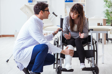 Fototapeta premium Male doctor examining female patient on wheelchair