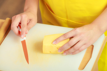 Woman hands cutting piece of cheese