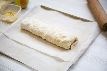 Raw apple pie or strudel with ingredients, side view.