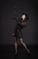 Beautiful young girl dancing in black tunic, black gloves and black hat.