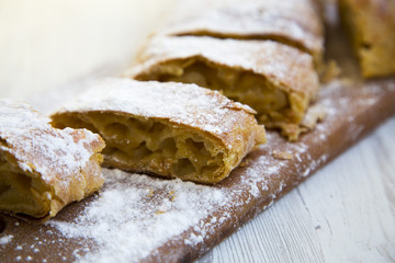 Strudel or apple pie on wooden board. Closeup