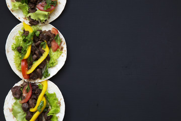 Mexican tacos with beef and fresh vegetables on a black background, top view. Copy space. Flat lay.
