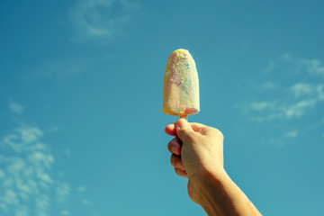 Ice cream in hand hold up.  on daytime and bright sky.