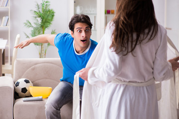 Young wife is trying to seduce husband from watching football an