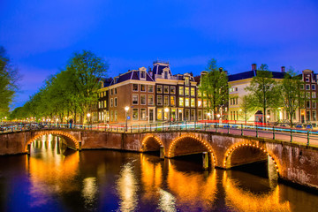 Fototapeta na wymiar Amsterdam canal with typical dutch houses during twilight blue hour in Holland, Netherlands.