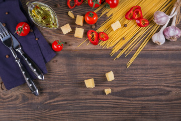 Ingredients for cooking spaghetti - raw pasta, tomato, olive oil, spices, herbs