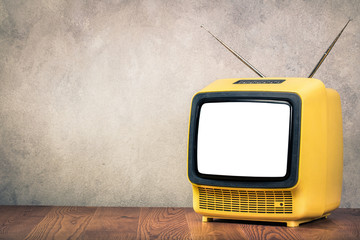 Retro old outdated yellow TV receiver from circa 60s on wooden table front textured concrete wall...