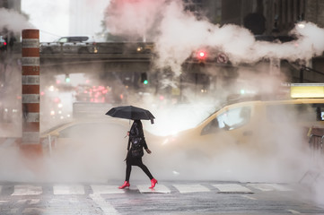 A woman with an umbrella and red high heels shoes is crossing the 42nd street in Manhattan. Taxi...