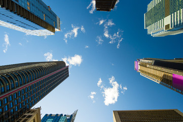 View from the bottom to top of some skyscrapers in Manhattan, blue sky and white clouds in the background. New York city, USA.