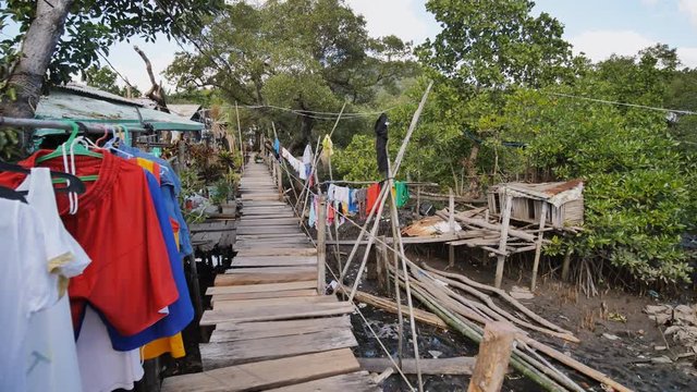 Houses of the poor in the Filipino slums. The swamp. Wooden bridges from planks on high water. Clothes on laces. Shooting in motion.