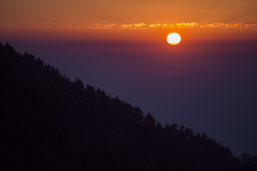 Amazing sunset behind a mountain with the silhouette of trees, Dharamsala, India.