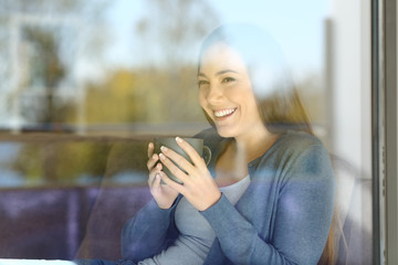 Woman drinking coffee loooking outside on a couch