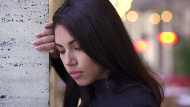 pensive and sad young asian woman thinking leaning against a wall