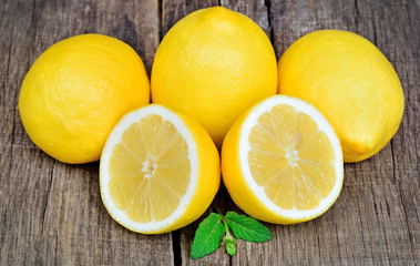 Fototapeta na wymiar Group of ripe whole yellow lemon citrus fruit with lemon fruit half on table