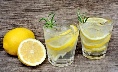 Water with fresh lemon and rosemary on wooden background